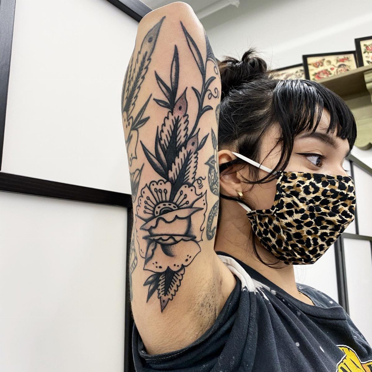 Tattoo of a flower and leaves on the back of a person's arm