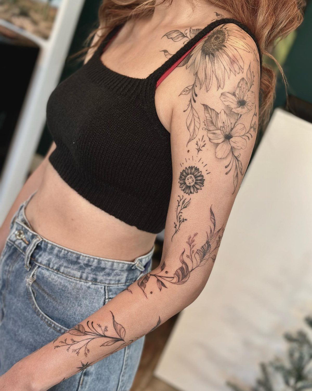 Woman with a large black floral tattoo on her bicep and upper arm.