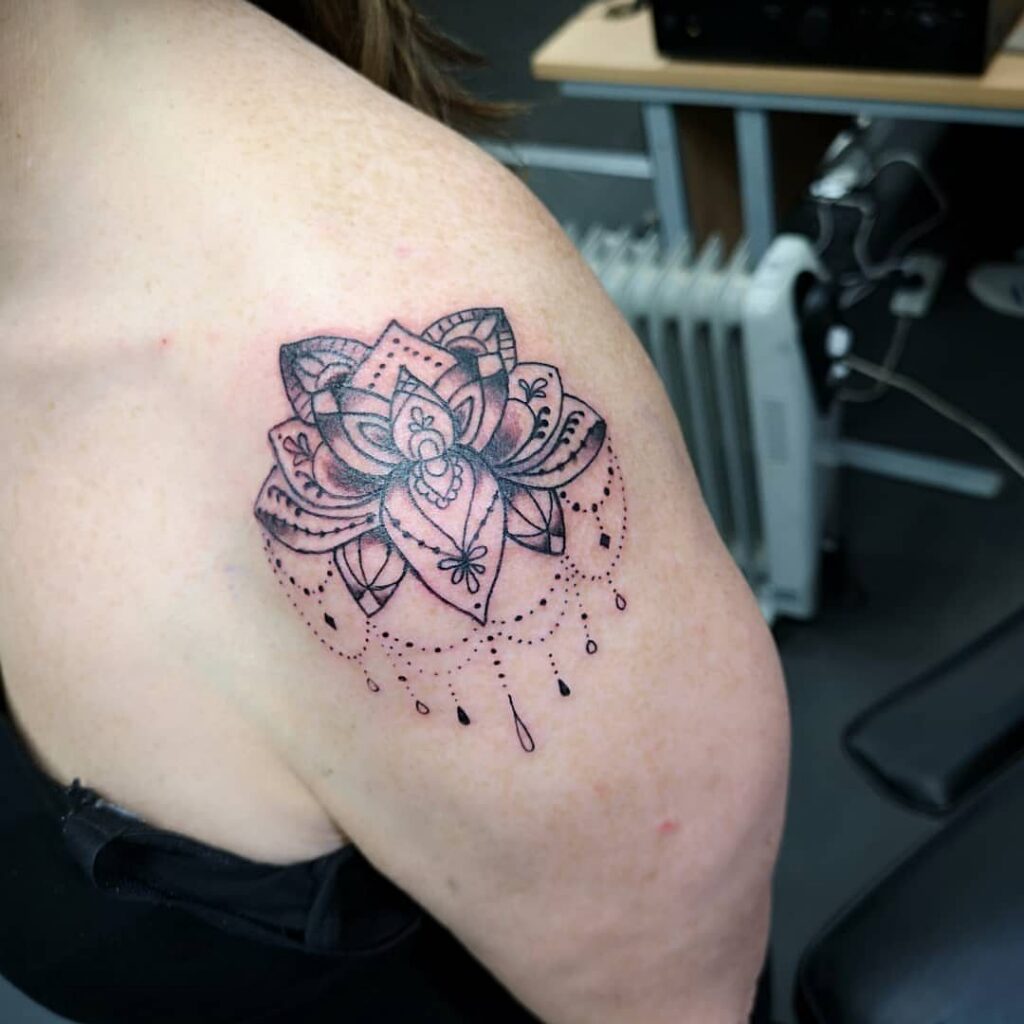 Lotus flower tattoo with geometric details on a person's shoulder