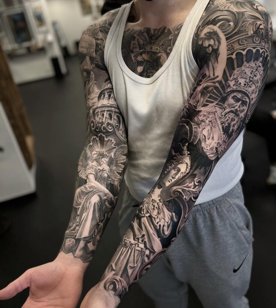 Man with detailed black and grey full arm tattoos and chest piece.