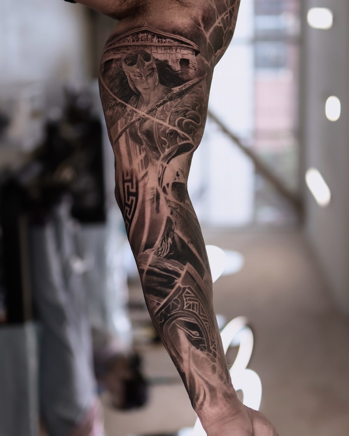Detailed black and grey full sleeve tattoo on a person's arm.