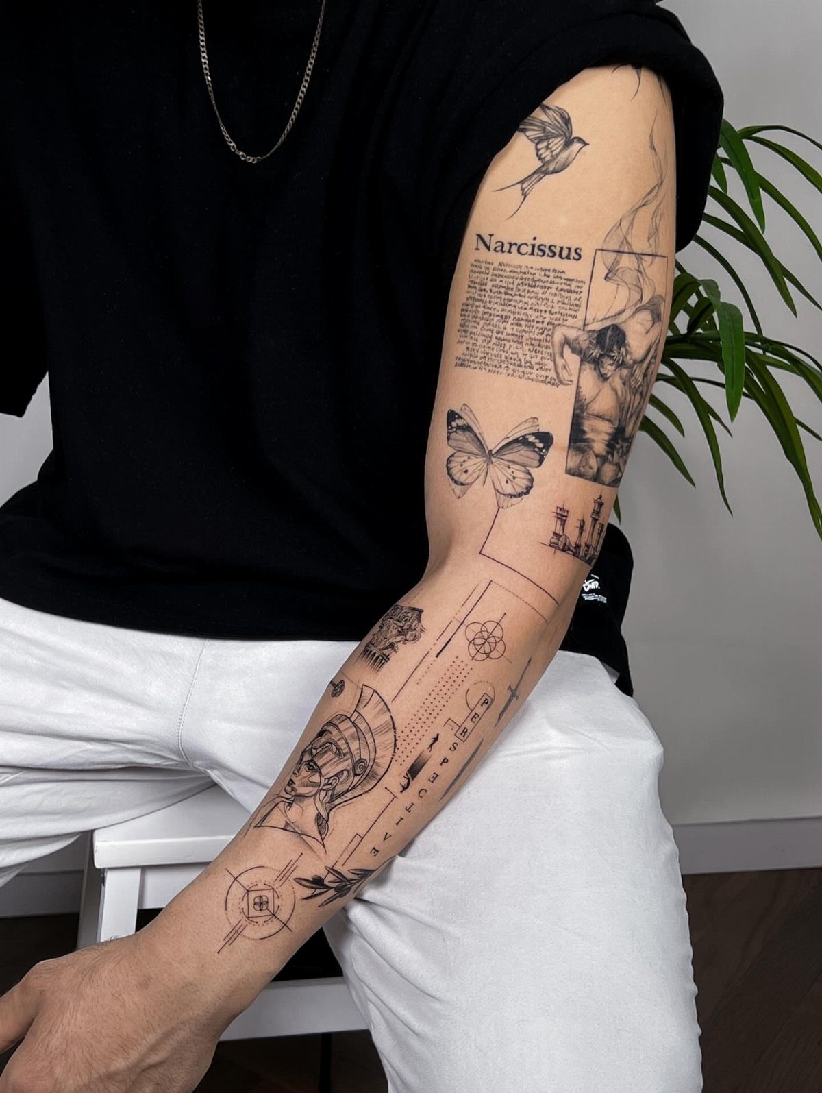 Man's arm with a detailed black ink tattoo sleeve featuring geometric shapes and figures.