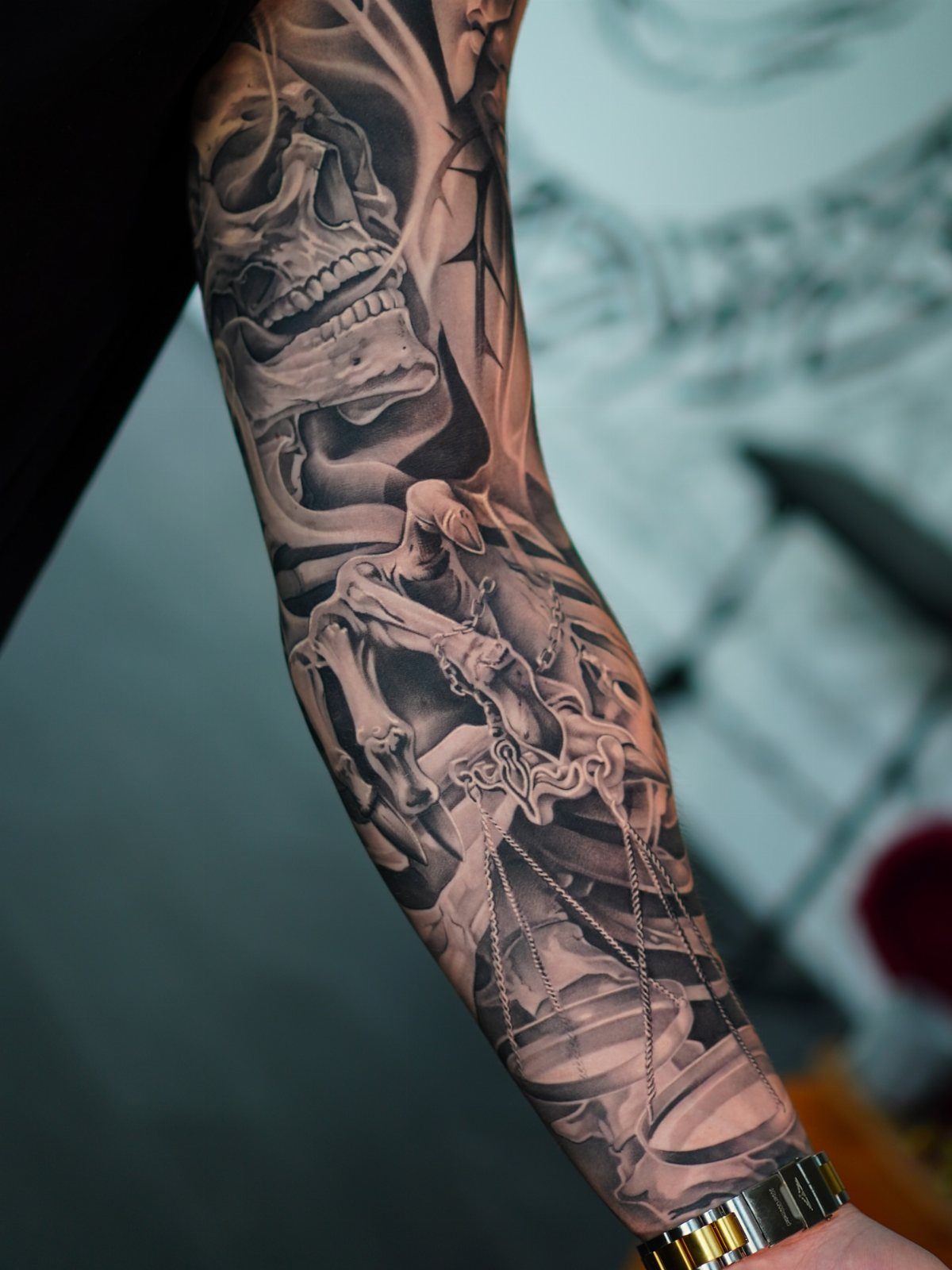 Inner arm tattoo featuring a detailed skull and a hooded grim reaper with scales.