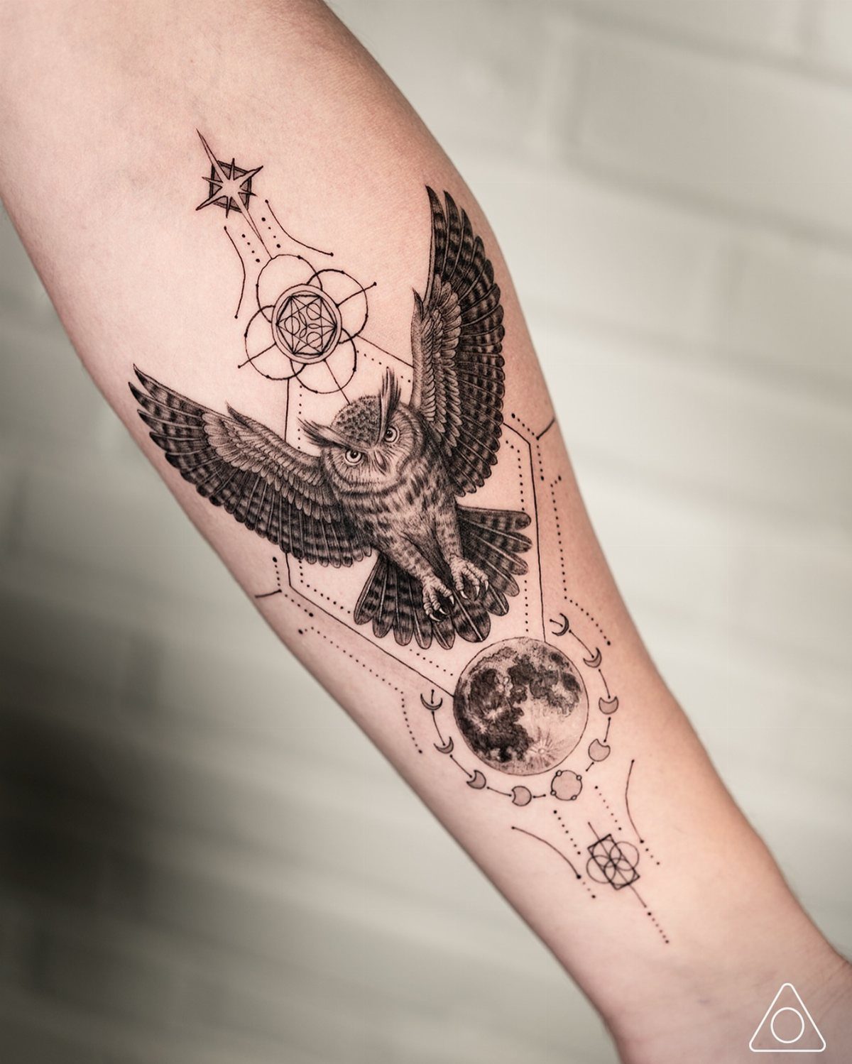 Inner forearm tattoo of an owl with a moon and geometric patterns.