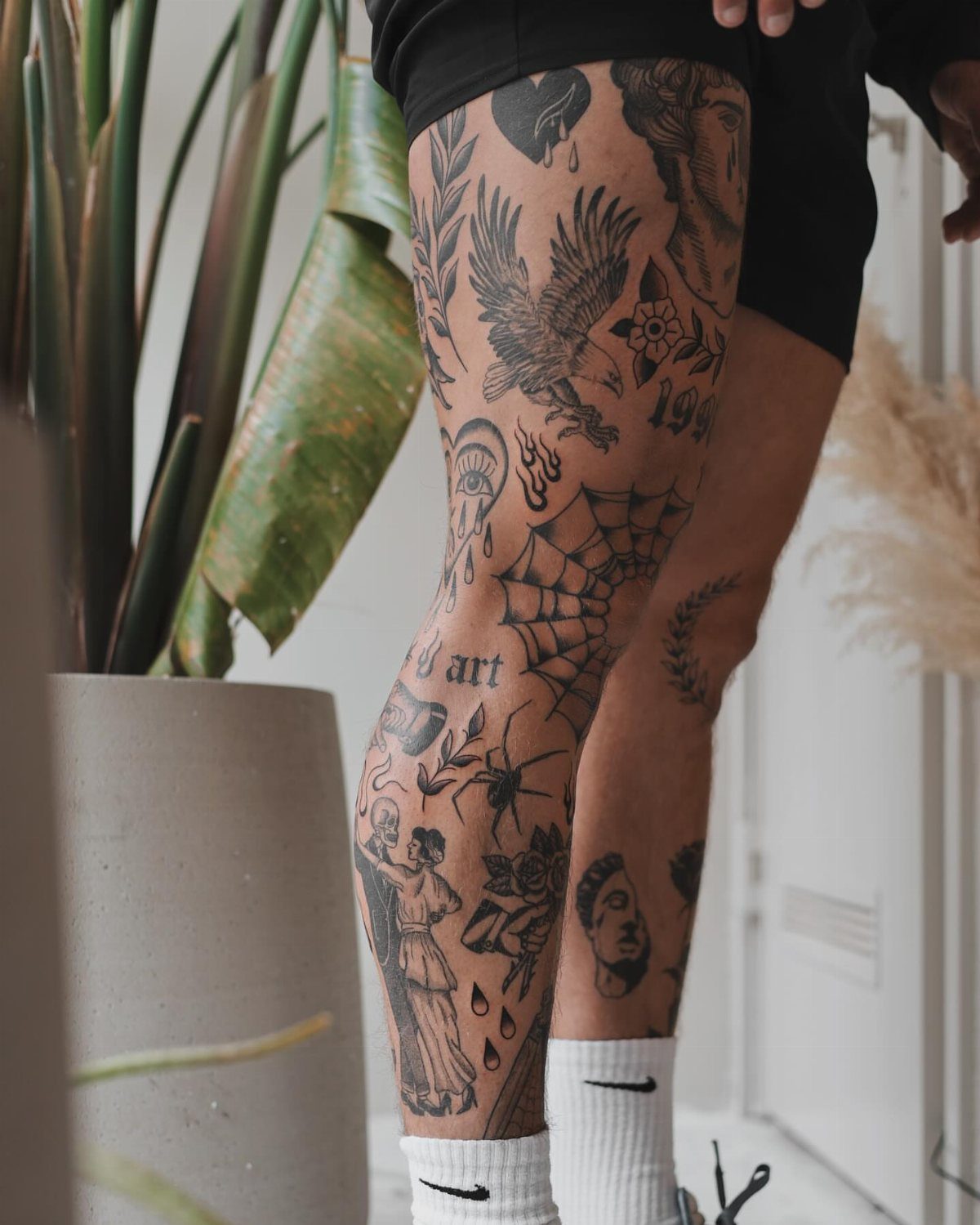 Patchwork leg sleeve tattoo with various black ink designs on a person's leg.