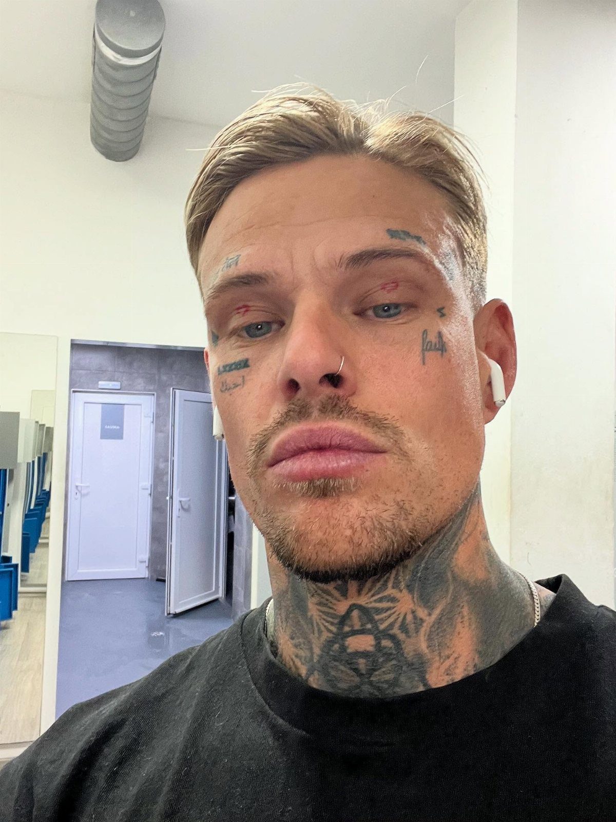 Man with black ink tattoos on his face and neck wearing a black shirt