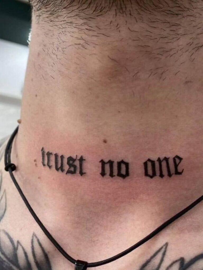 Man's neck with a black gothic tattoo reading trust no one