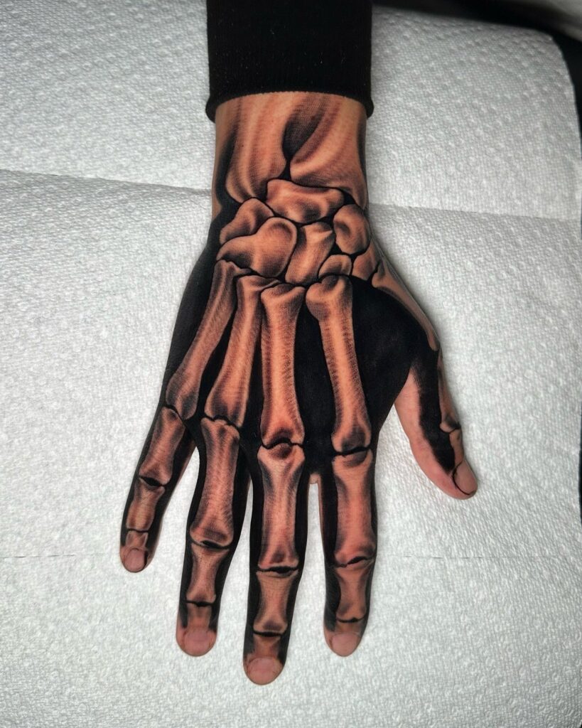 Skeleton hand tattoo on a human hand with realistic anatomical bone detailing.