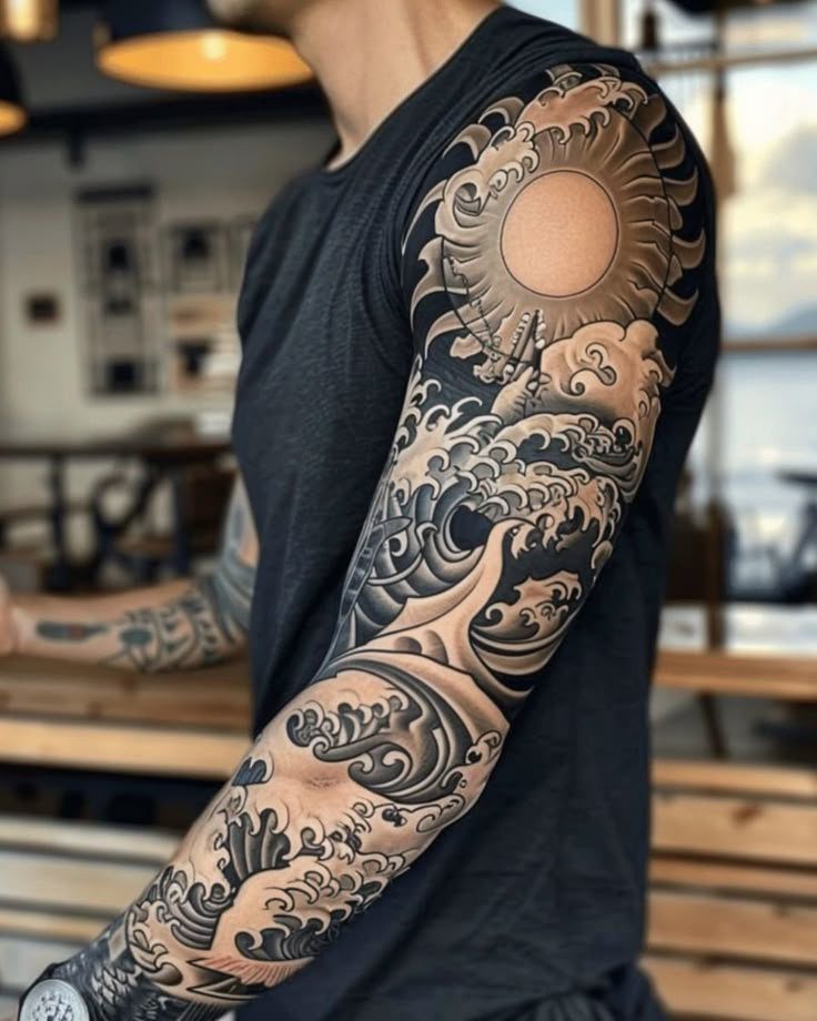 Man's arm featuring a detailed black and grey Japanese style wave tattoo sleeve.