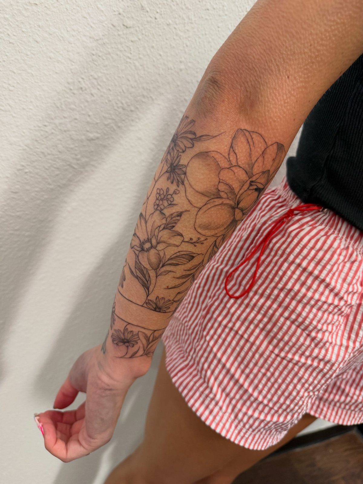 Floral black ink tattoo covering a person's arm from shoulder to wrist.