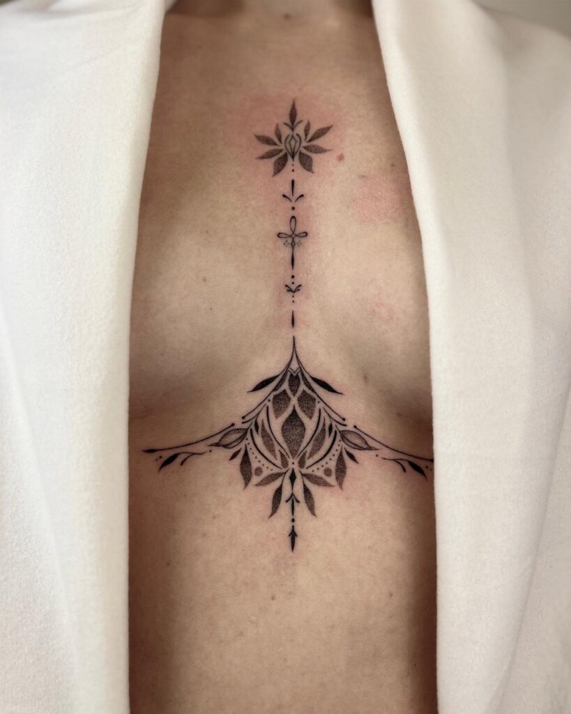 Ornamental black ink tattoo on a woman's chest and underboob area.