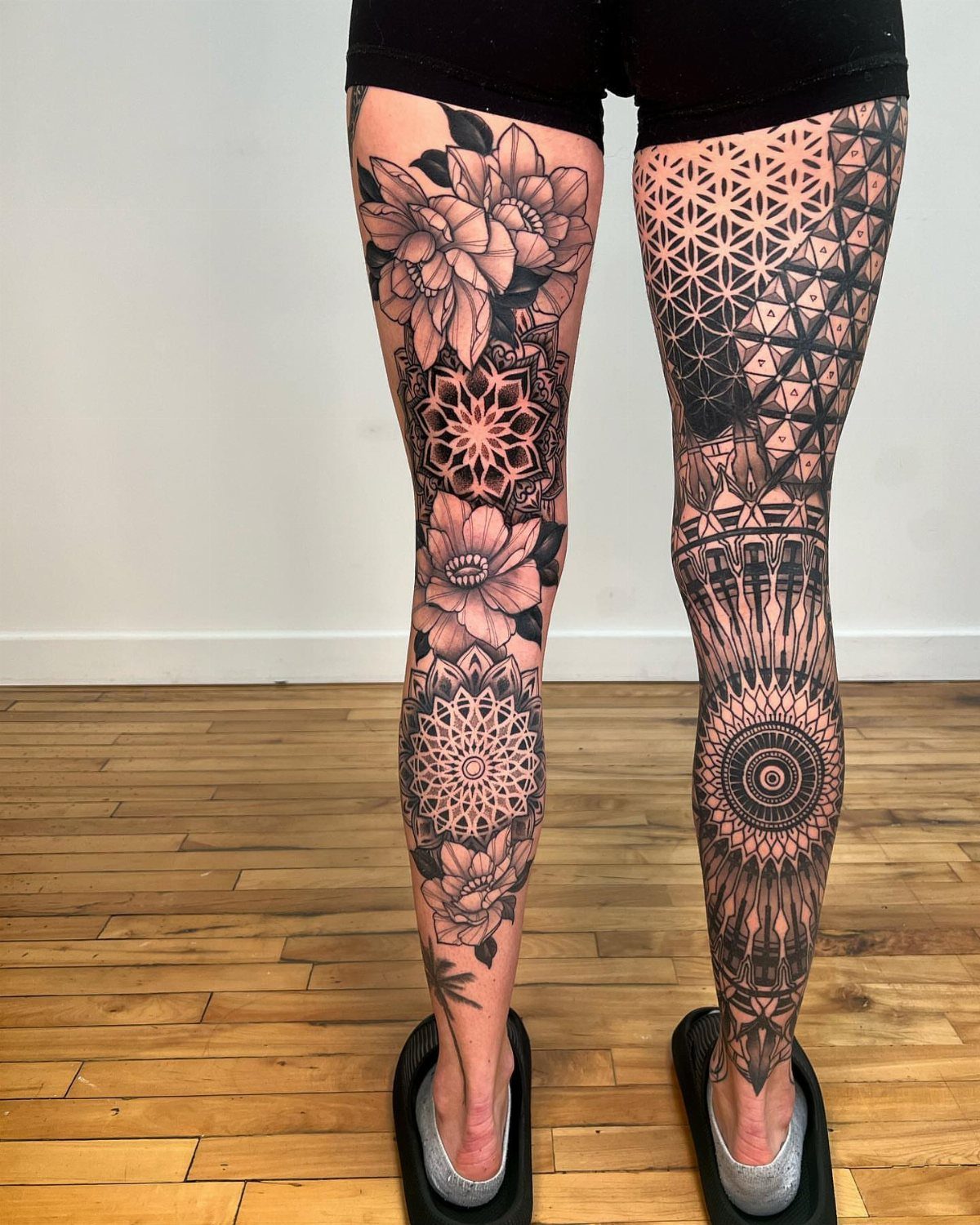 Legs with intricate black ink floral and geometric tattoos from thigh to ankle.
